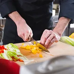 Chef cuisinier pratiquant des techniques de découpe professionnelle lors d'une formation Kalyane Consulting certifiée Akto.